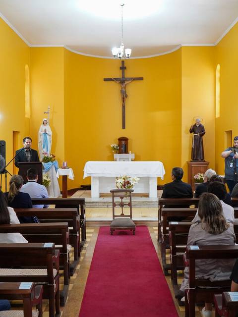 Una ceremonia religiosa se lleva a cabo en una iglesia con asistentes sentados y un altar decorado.