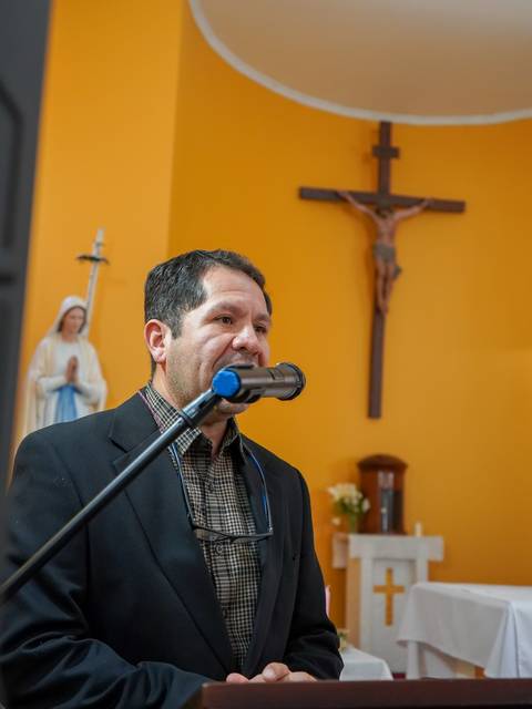 Un hombre habla en un altar de una iglesia con decoraciones religiosas.