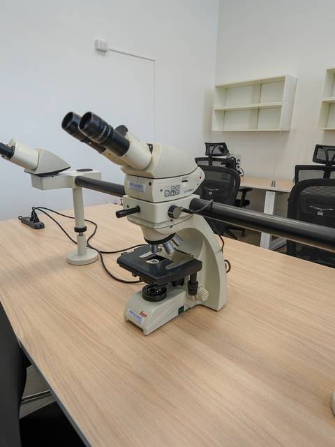 La imagen muestra un laboratorio con varios microscopios sobre una mesa de trabajo.