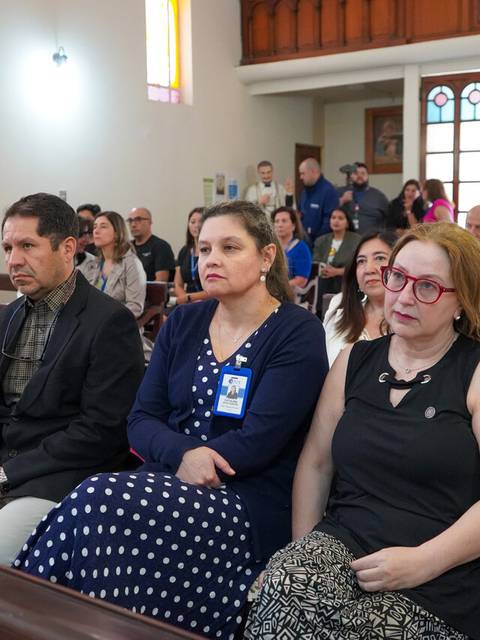Un grupo de personas sentadas en un banco dentro de una iglesia durante un evento.