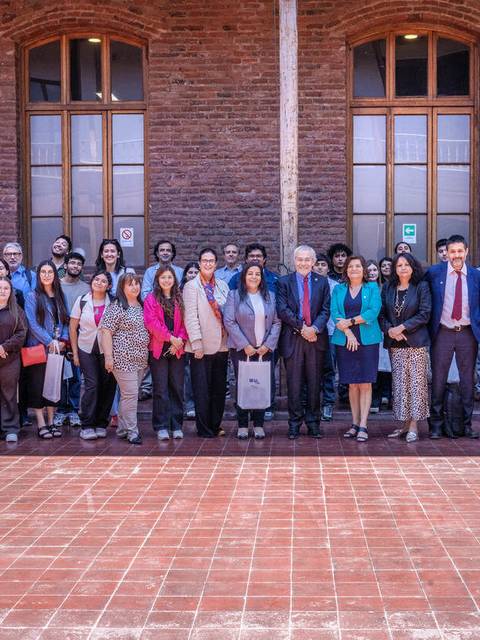 Grupo de personas posando en un evento en un edificio con ladrillos a la vista.