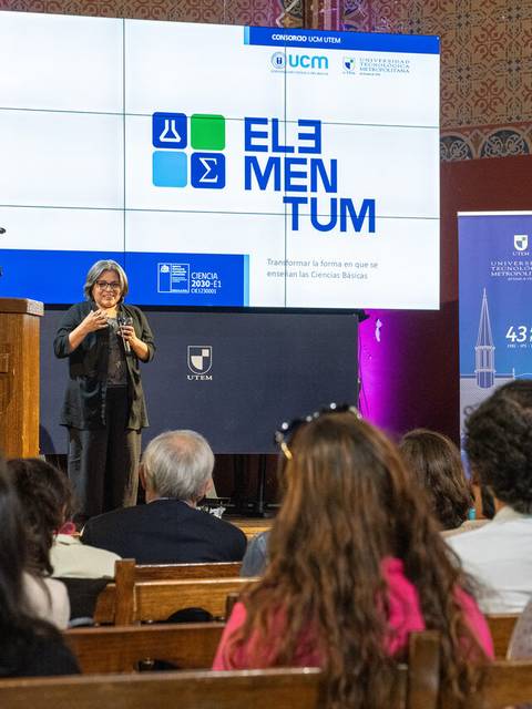 Una mujer está presentando en un evento con una pantalla de fondo que muestra el logo de 'Elementum'.