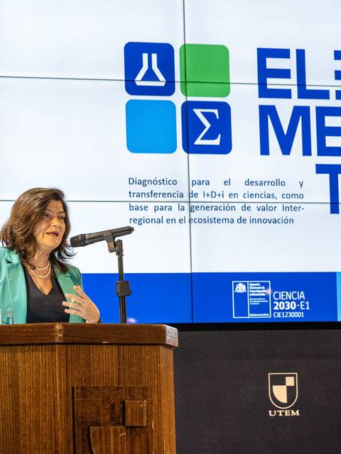 Una mujer habla en un evento académico frente a una pantalla que muestra el logo de un proyecto de innovación.