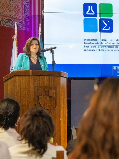 Una mujer habla desde un podio en un evento relacionado con la ciencia y la innovación.