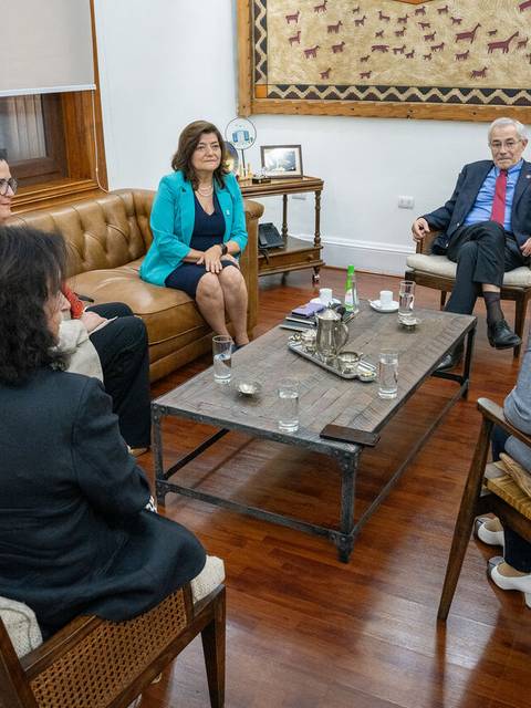 Un grupo de cinco personas reunidas en una sala de estar conversando con un ambiente formal.