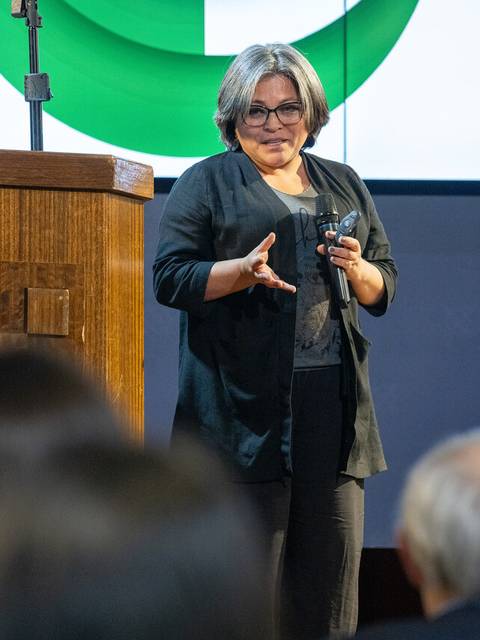 Una mujer está hablando frente a un público en un evento académico.