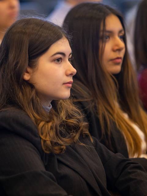 Un grupo de jóvenes escucha atentamente durante una presentación en un evento.