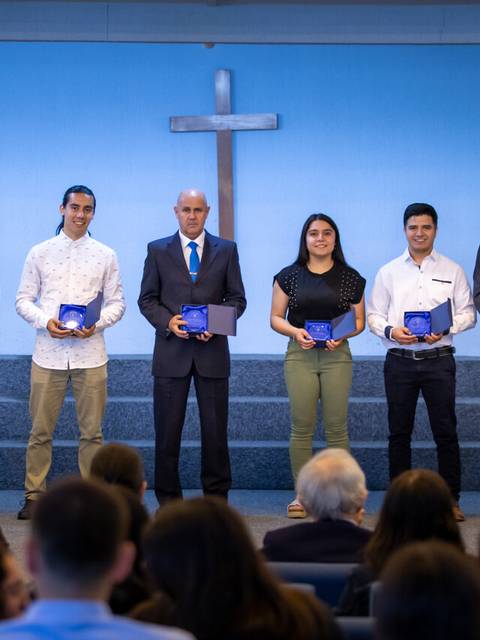 Un grupo de personas posando con diplomas en una ceremonia en un entorno religioso.