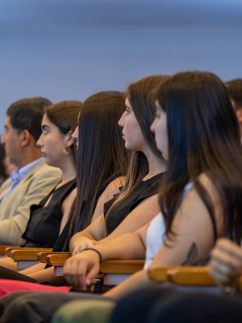 Un grupo de personas sentadas escuchando atentamente en un evento.