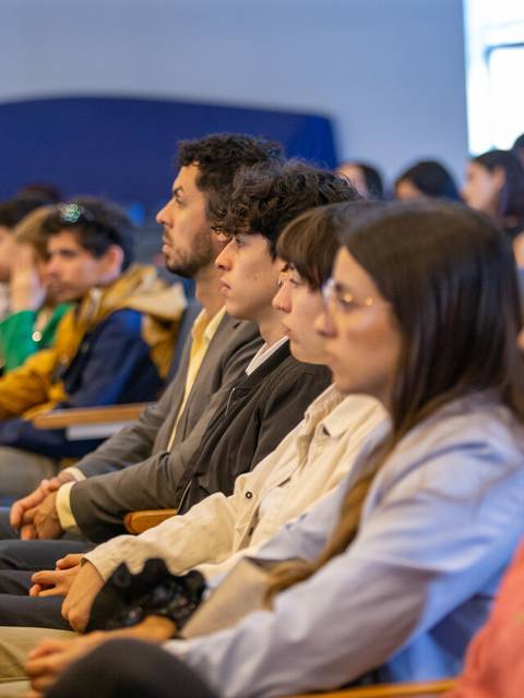 Un grupo de personas sentadas en un auditorio prestando atención a un evento.