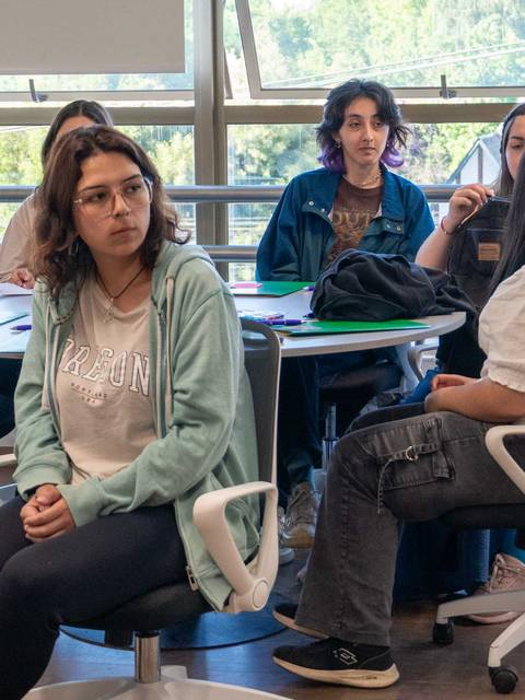 Un grupo de jóvenes sentados en un aula, participando en una conversación.