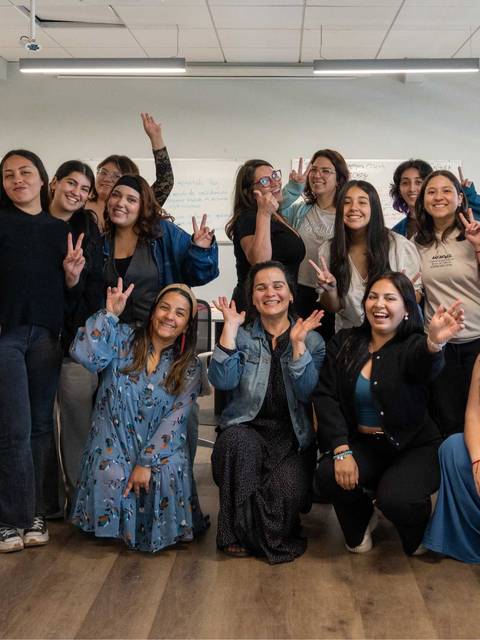 Grupo de mujeres sonriendo y posando juntas en un ambiente de oficina.