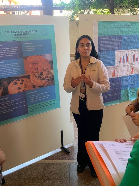 Una estudiante presenta un proyecto sobre galletas mientras otros escuchan atentamente.