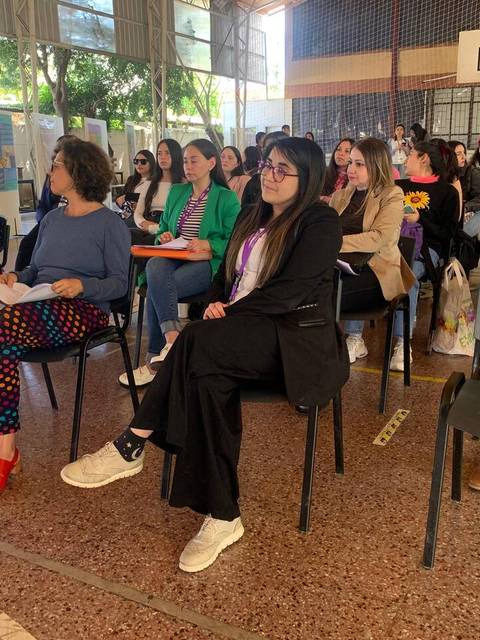 Un grupo de personas sentadas en un espacio interior durante una actividad o presentación.