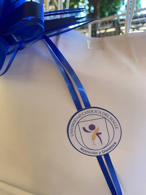 Una bolsa con un lazo azul y un logo de la Universidad Católica del Maule en el frente.