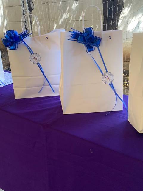 Un grupo de bolsas blancas decoradas con lazos azules sobre una mesa morada.