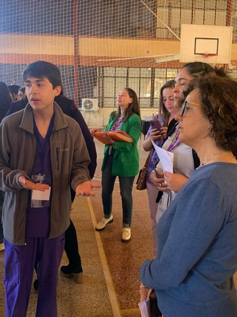 Un grupo de personas observa a un joven que presenta un proyecto en un entorno escolar.