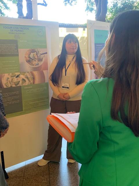 Un grupo de personas discutiendo frente a carteles de presentación en un evento académico.
