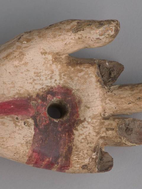 Una mano de figura escultórica con detalles pintados y un agujero en la palma.