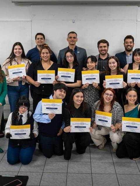 Grupo de personas posando con certificados en un ambiente académico.