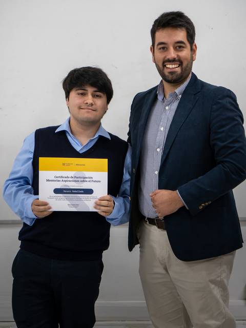 Dos personas posan juntas, una de ellas sostiene un certificado.