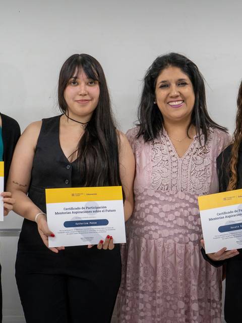 Cuatro personas sonríen mientras sostienen certificados en un evento académico.