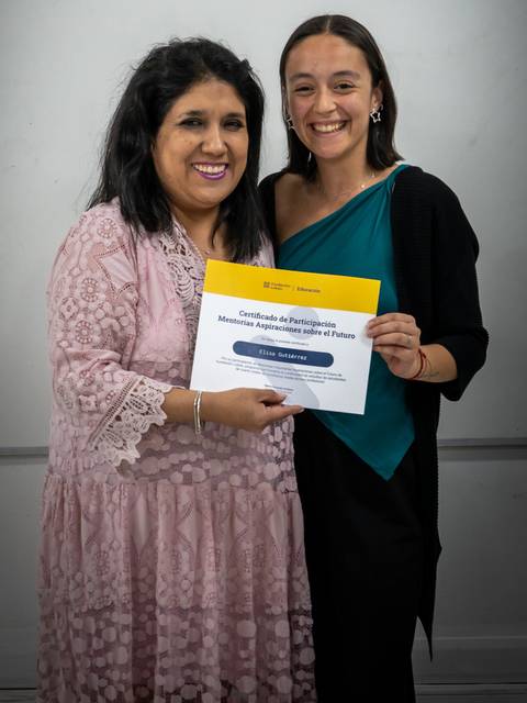 Dos mujeres posando sonrientes mientras sostienen un certificado.