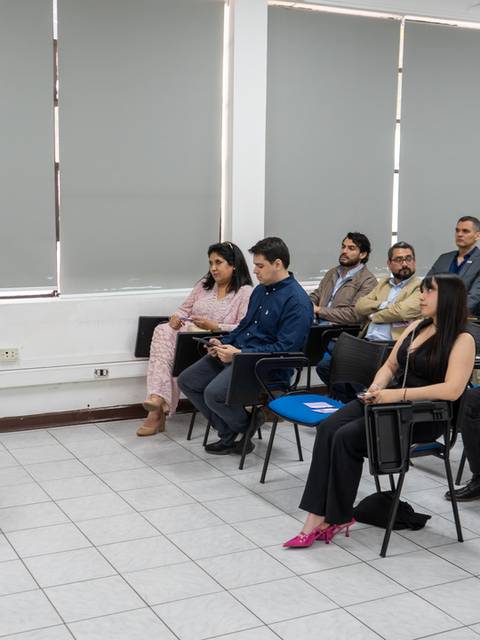 Un grupo de personas escucha a un orador en una sala de conferencias.