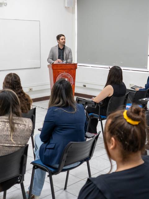 Una persona está dando una presentación frente a un grupo de personas en un aula.