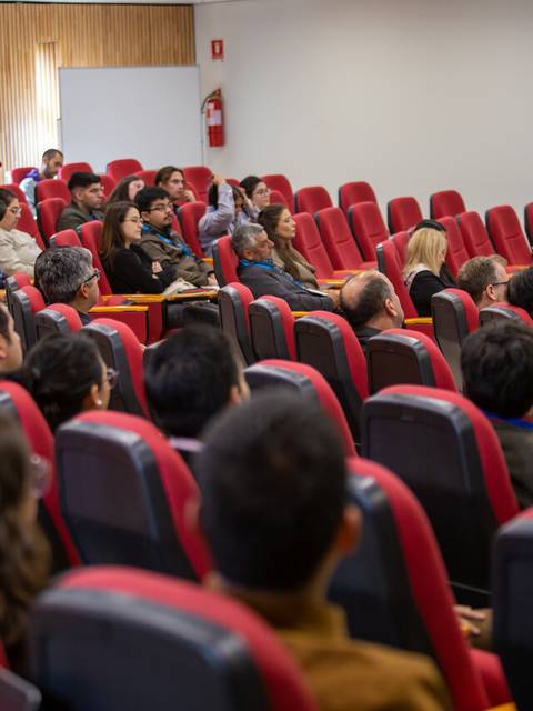 Un grupo de personas sentadas en un auditorio durante una presentación.