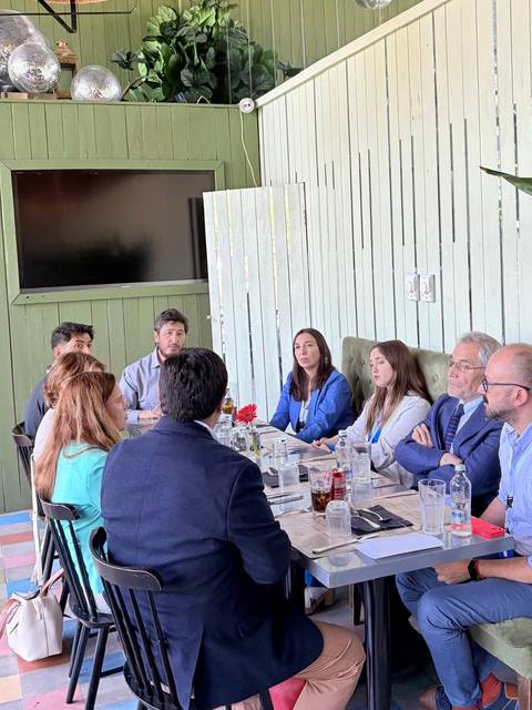 Un grupo de personas se encuentra sentada en una mesa en un ambiente acogedor y moderno, conversando durante una reunión.