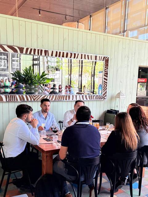 Un grupo de personas se reúne alrededor de una mesa en un restaurante con un ambiente moderno y colorido.