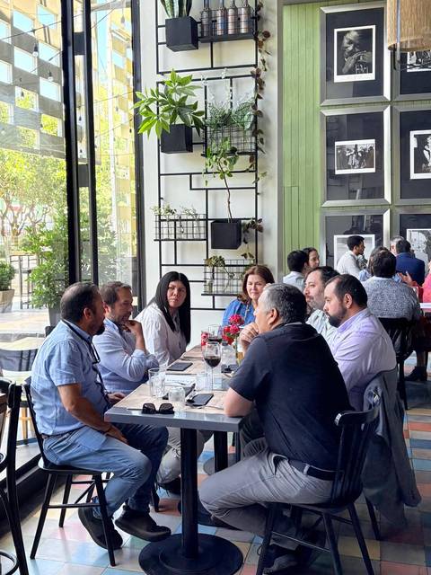 Un grupo de personas conversando alrededor de una mesa en un restaurante con decoración moderna.