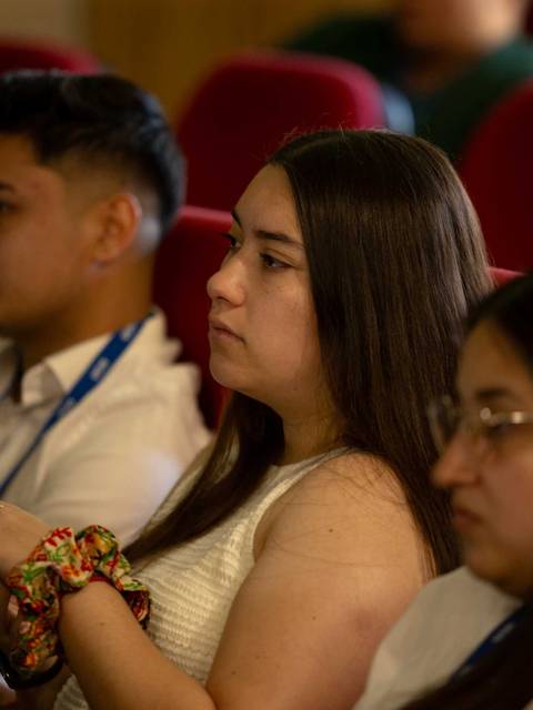 Un grupo de personas sentadas en un auditorio prestando atención durante un evento.