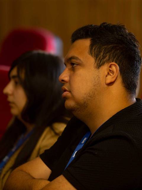 Dos personas sentadas en una sala, escuchando atentamente.