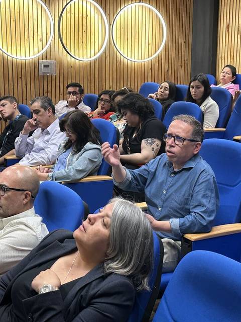 Un grupo de personas sentadas en un auditorio durante una presentación.