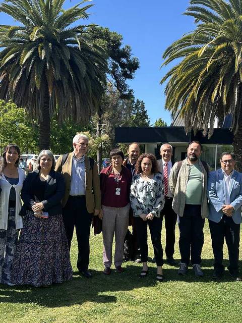 Un grupo de personas posando en un jardín con palmeras al fondo.