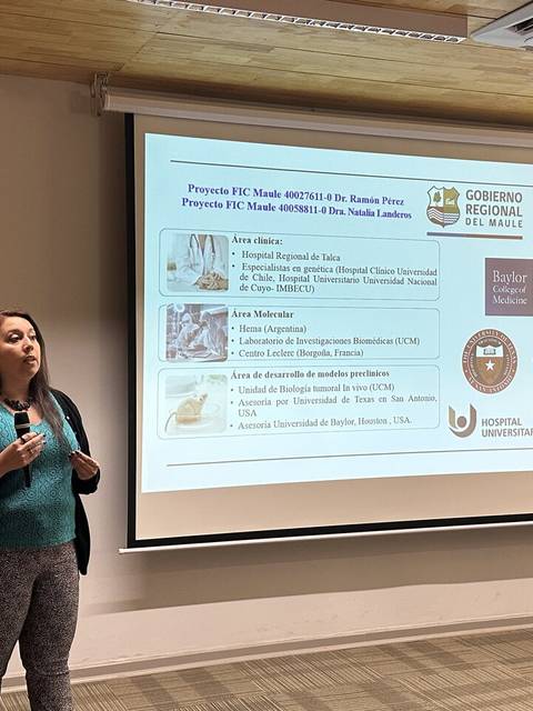 Una mujer presenta un proyecto frente a una pantalla con información y logos de diversas instituciones.