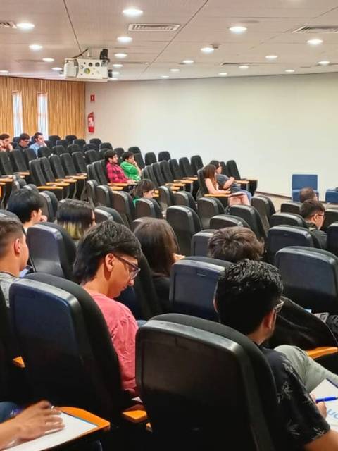 Una conferencia con un panel de discusión ante un auditorio lleno de estudiantes.