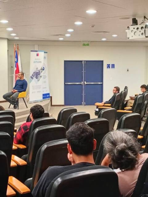 Una charla en un auditorio con una audiencia atenta frente a dos oradores en un panel.