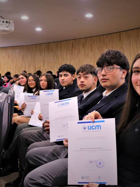 Estudiantes posando con sus certificados en un evento formal.