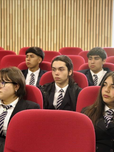 Un grupo de estudiantes sentados en un auditorio, prestando atención.