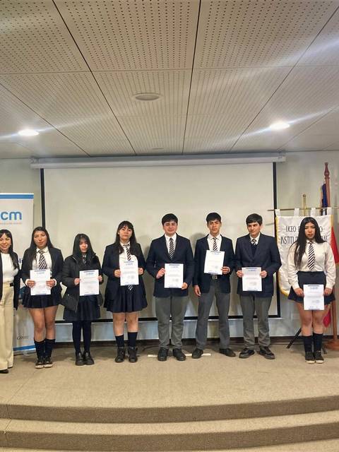 Un grupo de estudiantes sostiene diplomas en un evento de premiación.
