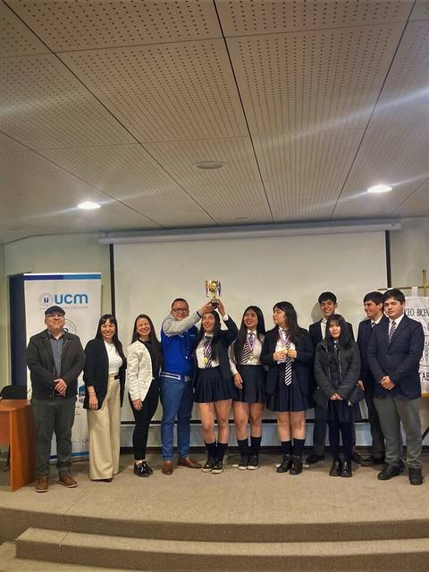 Un grupo de personas celebra la entrega de un trofeo en un evento académico.