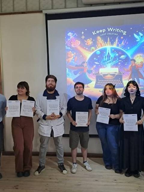 Un grupo de seis personas presenta certificados frente a una proyección colorida que dice 'Keep Writing'.