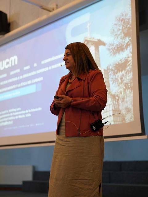 Una mujer se presenta en un evento con una proyección detrás de ella en un escenario.