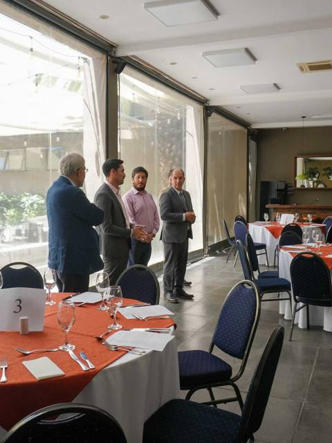 Una sala de recepción con mesas vestidas y un grupo de personas en conversación.