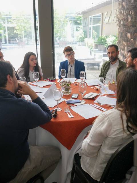 Un grupo de personas sentadas alrededor de una mesa compartiendo una conversación en un entorno acogedor.