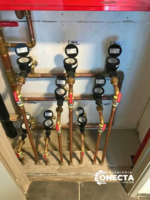 Instalación de contadores de agua en una pared, mostrando múltiples tuberías y manómetros.