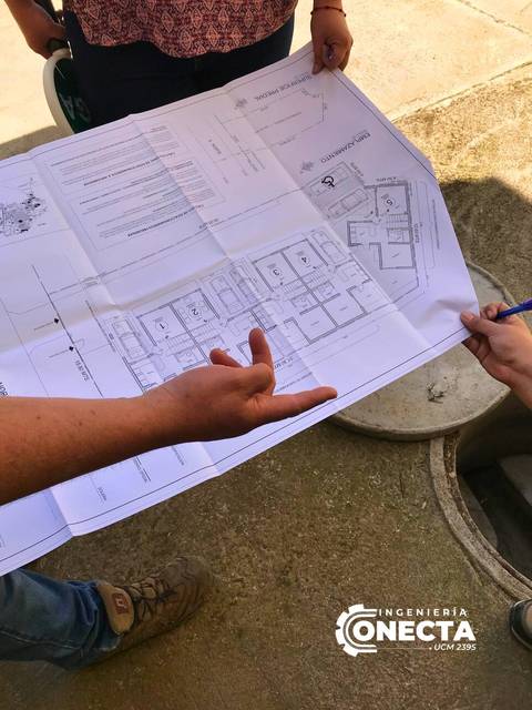 Un grupo de personas revisa un plano de construcción en un lugar de trabajo.